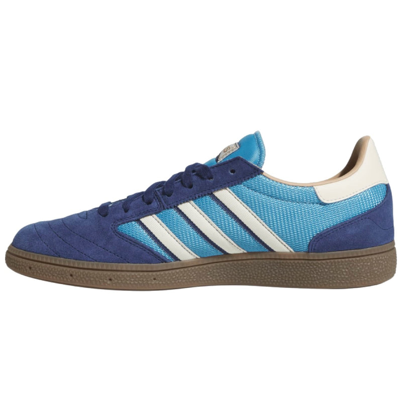 A low-top Adidas Busenitz sneaker in blue, featuring a suede and mesh upper, three white stripes, a light blue heel panel, and a brown gum sole.