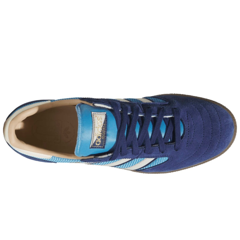 A single Adidas low-top sneaker shown from a top-down view, featuring a navy blue suede upper with light blue and white stripes, navy laces, and a light beige interior lining.