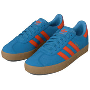 A pair of Adidas Gazelle sneakers in blue suede with bright orange stripes and a gum sole.