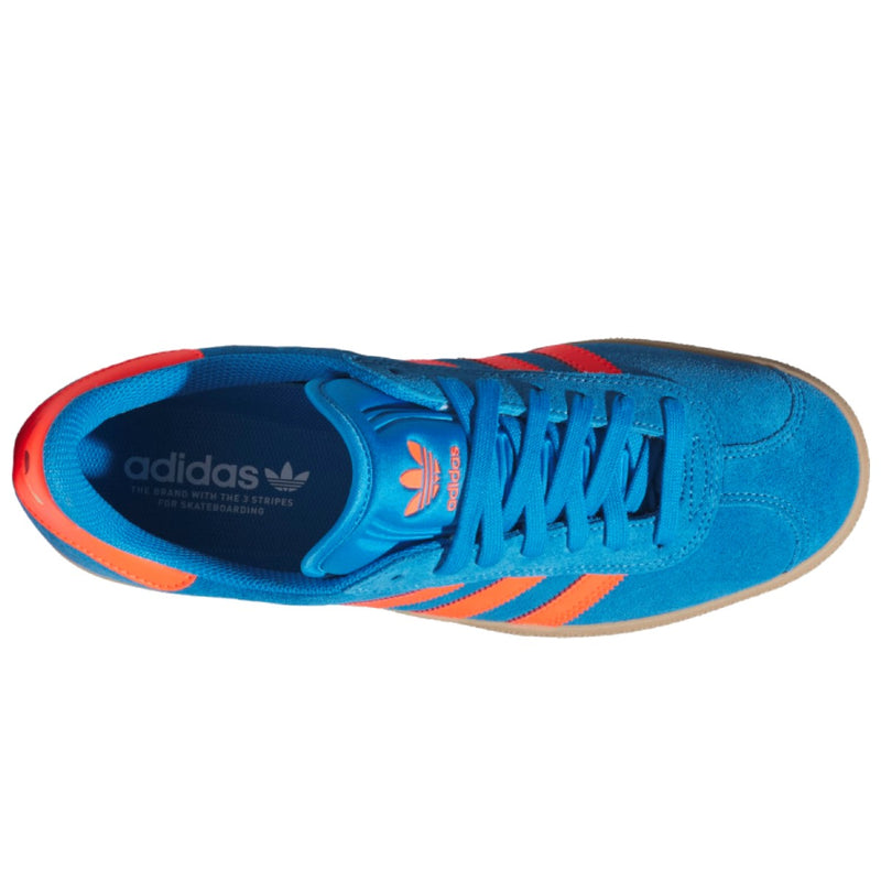 A single Adidas Gazelle sneaker shown from a top-down view, featuring a vibrant blue suede upper with bright orange stripes and accents, blue laces.