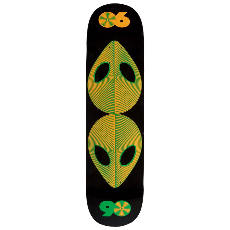 A skateboard deck with a black background, featuring a symmetrical alien head graphic in yellow and green, with orange and green logo graphics at the top and bottom.