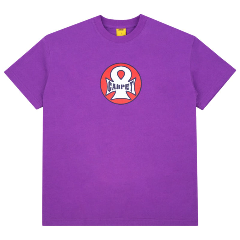 A purple short-sleeve crewneck t-shirt featuring a circular chest graphic with a white stylized 'C' logo and the word 'CARPET' in white on a red and pink background.