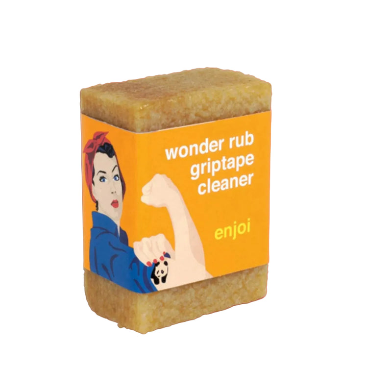 A rectangular bar of Enjoi Wonder Rub Griptape Cleaner, featuring a bright orange label with a classic Rosie the Riveter illustration and white text, set against a solid coral pink background.
