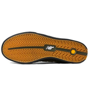 The outsole of a New Balance shoe, featuring a textured orange-brown herringbone pattern with a black center stripe and a yellow Vibram logo near the heel.