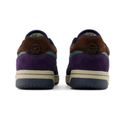 New Balance Numeric 480 x 35th North A pair of low-top sneakers shown from the back, featuring brown suede overlays, a purple suede heel section, a dark navy collar, a teal side stripe, and a cream midsole.