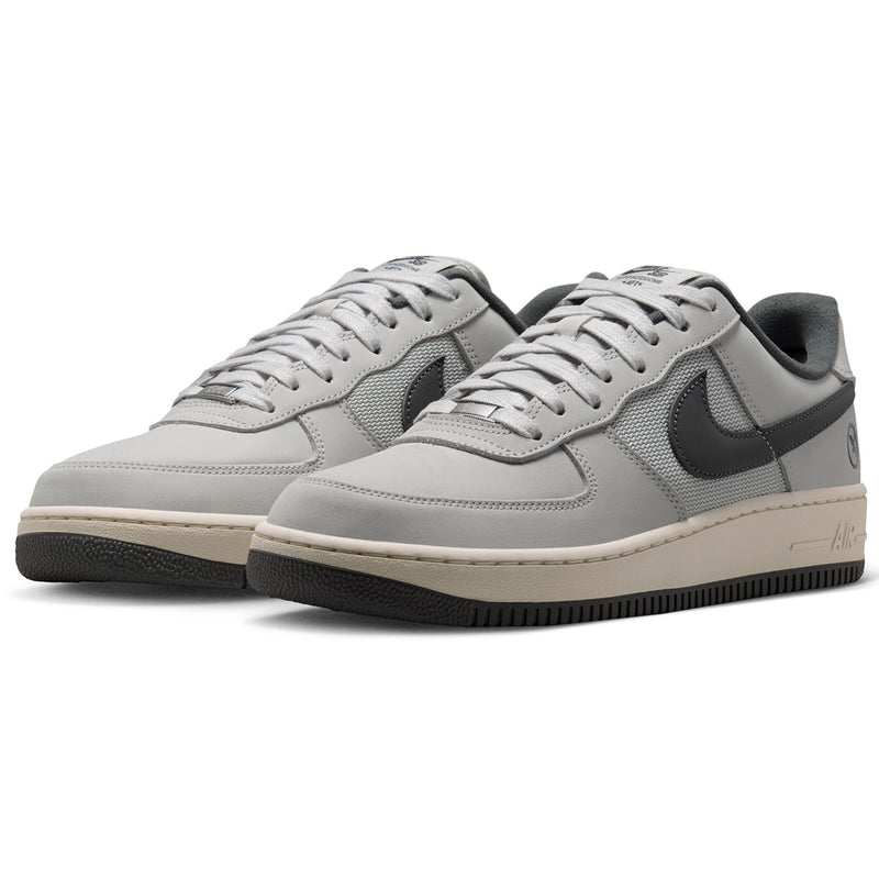  Nike SB Air Force 1 x Yuto sneakers in light gray and black, featuring a light gray leather and mesh upper, black Swoosh, and a beige midsole with a black outsole.