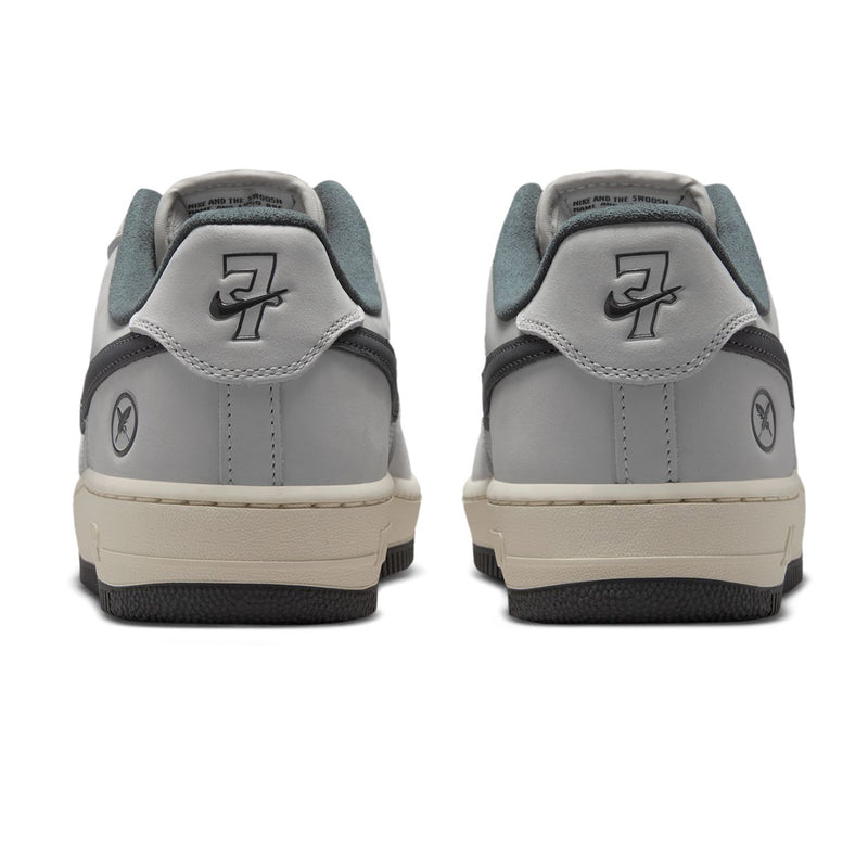 Nike SB Air Force 1 x Yuto sneakers shown from the back, featuring a light gray leather upper with dark gray overlays, a light gray heel tab with a stylized '7' logo, and a cream-colored midsole.