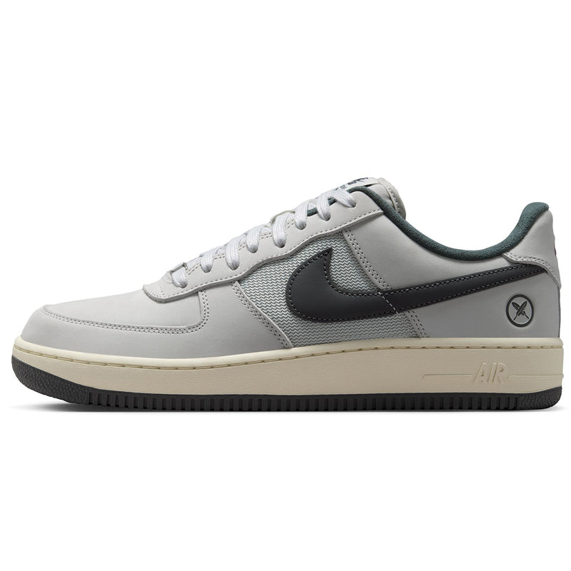  Nike SB Air Force 1 x Yuto sneaker in light gray and dark gray, featuring a cream-colored midsole and a black outsole, shown from a side profile view on a white background.