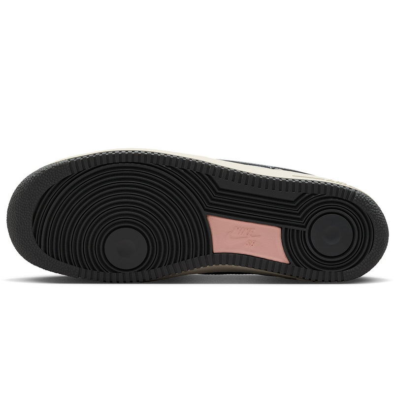 The bottom sole of a  Nike SB Air Force 1 x Yuto sneaker, featuring a black textured rubber outsole with a metallic pink heel tab.