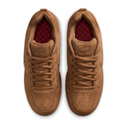 A pair of Nike SB Paul Rodriguez sneakers in a monochromatic tan suede and leather finish, featuring a red checkered pattern visible on the inner lining.