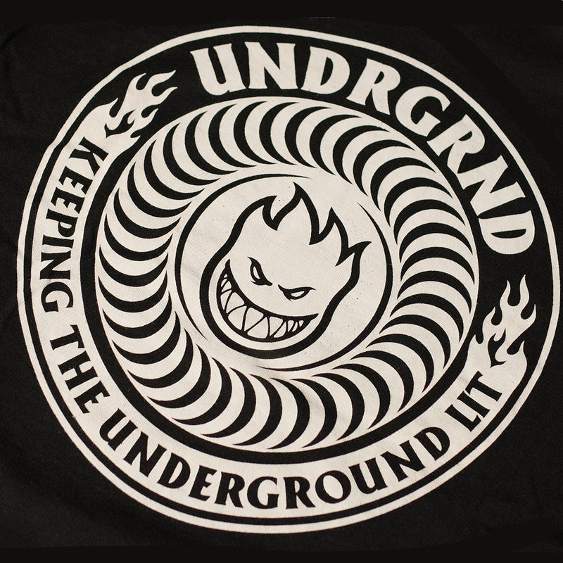 A close-up of a black circular graphic print featuring a white stylized snake coiling around a snarling face, with the text 'UNDRGRND' and 'KEEPING THE UNDERGROUND LIT' in white.