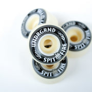Four skateboard wheels stacked in a cluster on a clean white background, featuring cream-colored urethane and black outer rings with white text reading 'UNDGRND' and 'SPIT FIRE'.